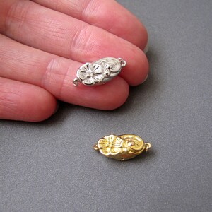 May include: Two flower-shaped clasps for jewelry making. One is silver and the other is gold.