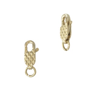 May include: Two gold-toned lobster clasps with a textured diamond pattern.