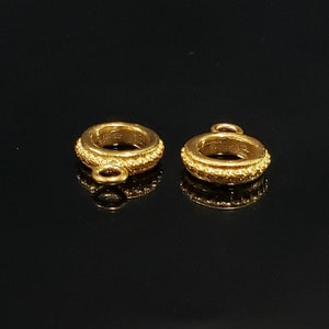 May include: Two gold-toned metal ring connectors with a textured surface and a small loop on each side. The connectors are designed for jewelry making.