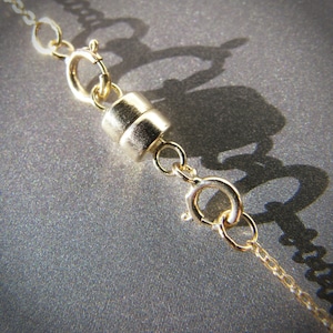 Peut inclure: Un collier en chaîne dorée avec un fermoir magnétique. Le fermoir est composé de deux pièces rondes de métal qui s'emboîtent.