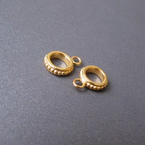 May include: Two gold-colored metal ring-shaped jewelry findings with a textured surface and a small loop on one side.