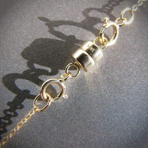 May include: Gold magnetic clasp for a necklace or bracelet. The clasp is made of two pieces that connect with a magnetic force.