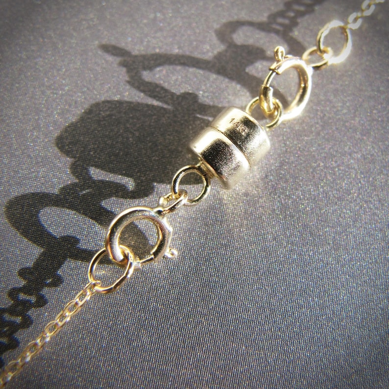 May include: Gold magnetic clasp for a necklace or bracelet. The clasp is made of two pieces that connect with a magnetic force.