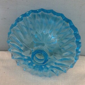 K&ouml;nnte beinhalten: Ein hellblauer Glasflaschenverschluss mit geriffeltem Design. Der Verschluss hat eine runde &Ouml;ffnung in der Mitte.