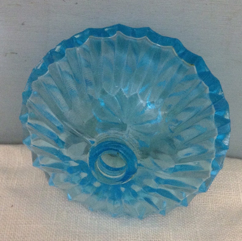 K&ouml;nnte beinhalten: Ein hellblauer Glasflaschenverschluss mit geriffeltem Design. Der Verschluss hat eine runde &Ouml;ffnung in der Mitte.