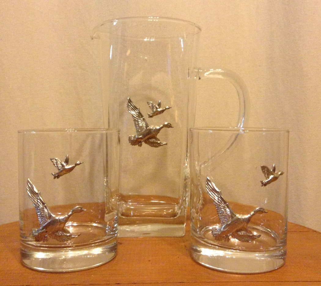 Close-up on a cocktail glass with three tiny ducks swimming in the