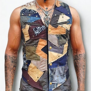 May include: A sleeveless vest constructed from a patchwork of various fabric swatches in shades of blue, brown, tan, and grey. The garment features exposed stitching, metal eyelets, brass-colored snap buttons, and two horizontal zippered chest pockets.