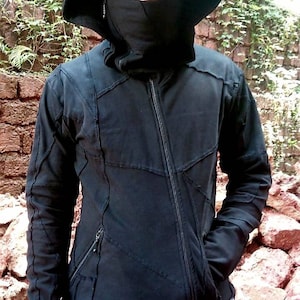 May include: A black hooded jacket with a zip fastening and a unique patchwork design. The jacket has a high collar and a face mask.