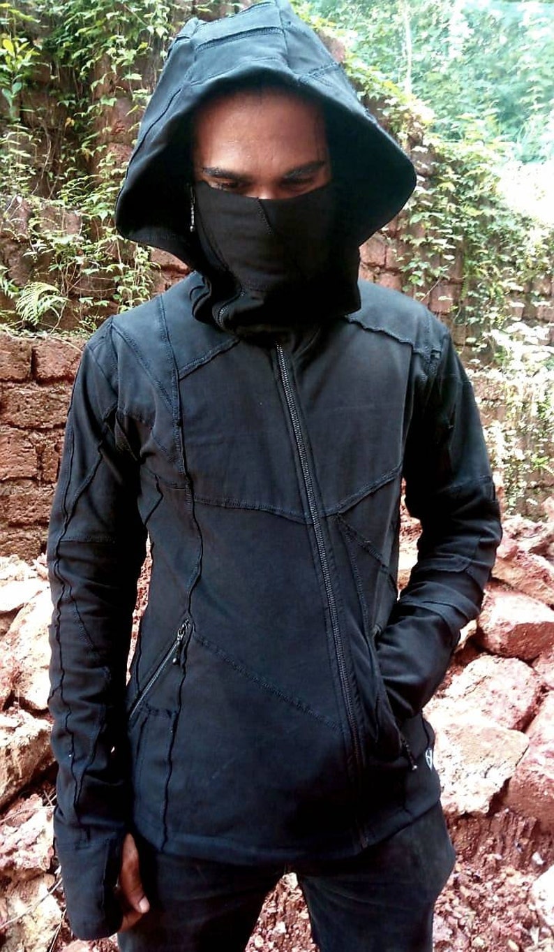 May include: A black hooded jacket with a zip fastening and a unique patchwork design. The jacket has a high collar and a face mask.
