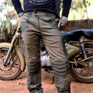 May include: Black long-sleeve shirt with a skull graphic and the text "CIRCUS TATTOOS". The shirt is paired with olive green cargo pants featuring ribbed knee and shin details. A motorcycle is visible in the background.