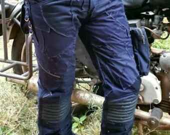 May include: Dark blue denim pants with multiple pockets and straps. The pants have knee pads and are worn with black boots.