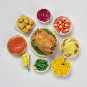 Peut inclure: Un ensemble miniature de dîner de Thanksgiving avec une dinde rôtie, de la purée de pommes de terre, de la sauce, des haricots verts, de la farce, de la sauce aux canneberges et des petits pains.