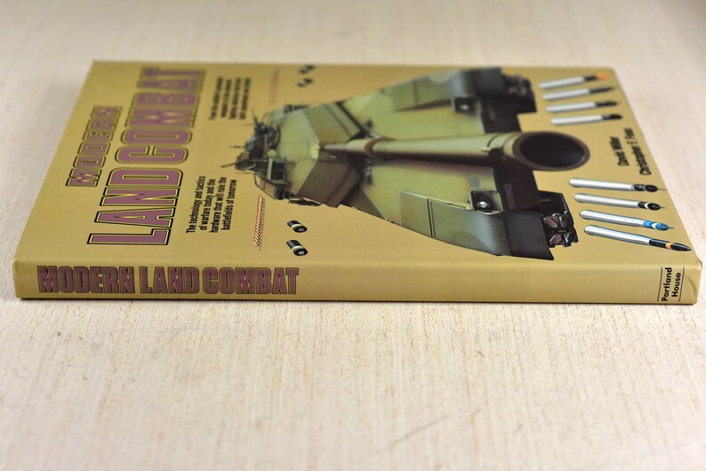 May include: A tan book titled "Modern Land Combat" with a picture of a military tank on the cover. The book is by David Miller and Christopher F. Foss and published by Portland House.