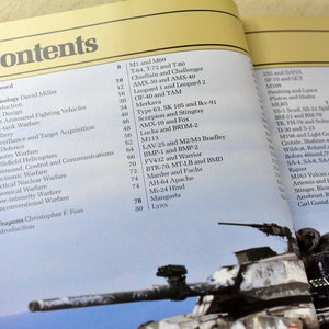 May include: A close-up of a book titled "Modern Fighting Vehicles" with a table of contents listing various military vehicles, including tanks, armored fighting vehicles, helicopters, and aircraft. The book is open to a page with a picture of a tank.
