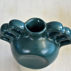 Pode incluir: Um vaso de cer&acirc;mica verde escuro com tr&ecirc;s al&ccedil;as. O vaso tem um corpo arredondado e uma abertura larga.