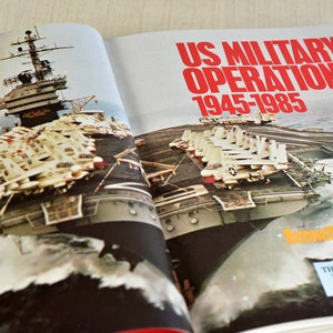 Pode incluir: Um livro aberto intitulado "US Military Operations 1945-1985" de Kenneth Anderson. O livro apresenta uma fotografia de um porta-avi&otilde;es com ca&ccedil;as na plataforma.