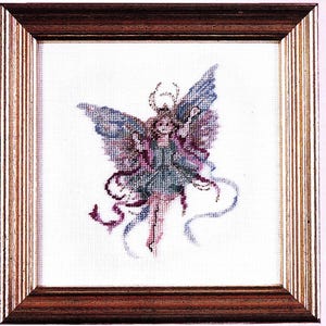 May include: A framed cross-stitch embroidery of a purple and blue angel with wings outstretched, holding a small white object in its hand. The angel is surrounded by white and purple ribbons.