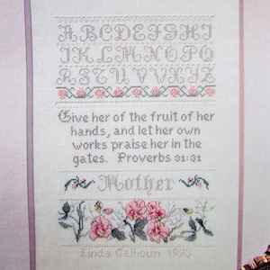 May include: Cross stitch pattern featuring a pink and green floral design. The pattern includes the alphabet, a bible verse, and the word "Mother".