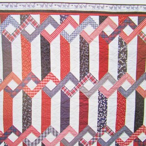 Puede incluir: Una colcha roja, blanca y azul con un patrón geométrico. La colcha está hecha de varias telas, incluyendo cuadros, vichy y estampados florales.