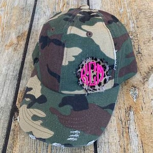 Op de afbeelding: Camouflage baseballpet met een verweerde look en een roze en luipaardprint monogram patch.