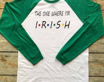 May include: White long-sleeve t-shirt with green sleeves. The shirt has a graphic print that says "The One Where I'm I.R.I.S.H" in a font similar to the popular TV show "Friends".