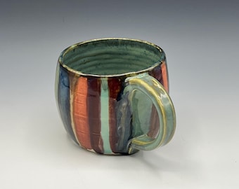 Wheel-thrown mug with turquoise handle and rich, colored hand-painted stripes