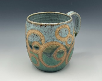 Wheel-thrown hand-painted mug in two styles with light blue and weathered bronze glaze