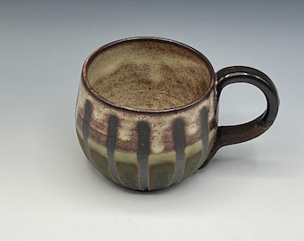 Wheel-thrown mug with wax resist stripes enhanced with a brown glazes