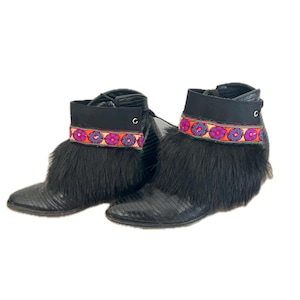 May include: A pair of black leather ankle boots with a fur trim and colorful embroidered bands around the ankle.