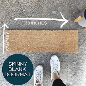 May include: A brown coir doormat with the text "SKINNY BLANK DOORMAT" on a blue circle. The doormat measures 76.2 cm long and 22.9 cm wide.