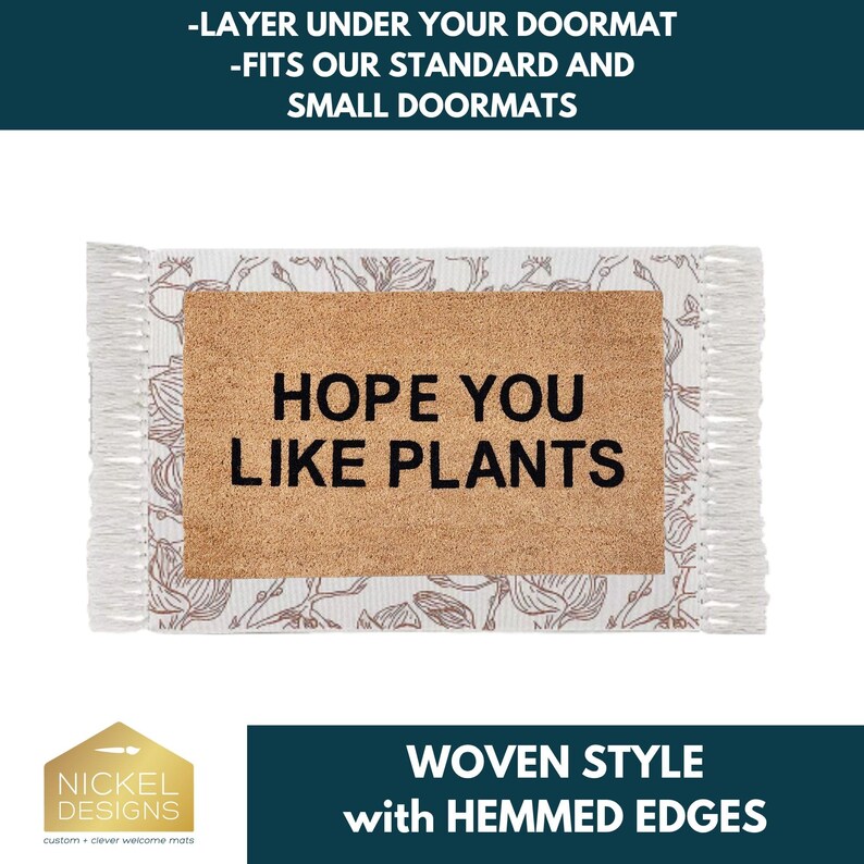 May include: A rectangular doormat layer featuring a central tan coir section with the black text HOPE YOU LIKE PLANTS. The border is white fabric with a brown floral line drawing pattern and fringed edges on the left and right sides.