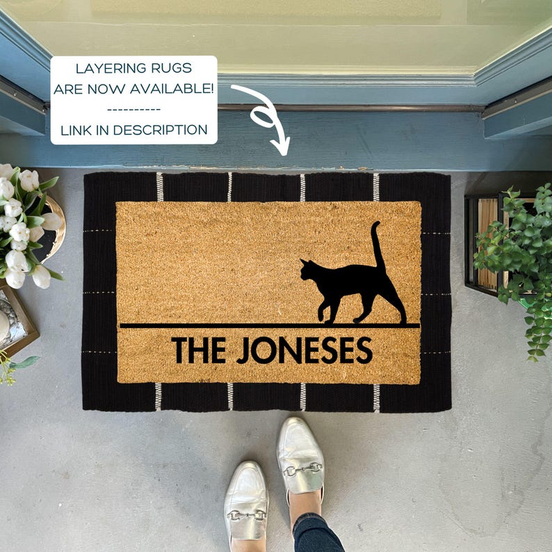 May include: Black and white doormat with a black cat silhouette and the text "THE JONESES" in white. The doormat has a black and white striped border.
