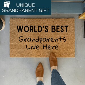 May include: A brown coir doormat with the text "WORLD'S BEST Grandparents Live Here" in black lettering.