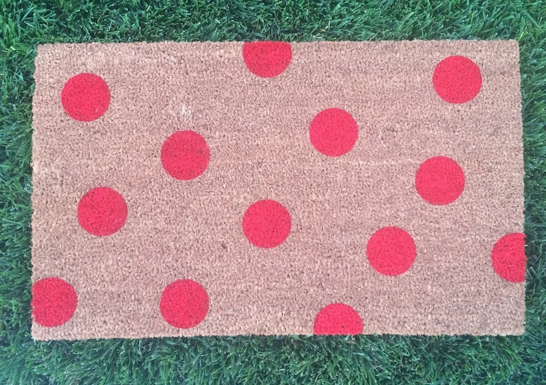 May include: A brown coir doormat with a red polka dot pattern.
