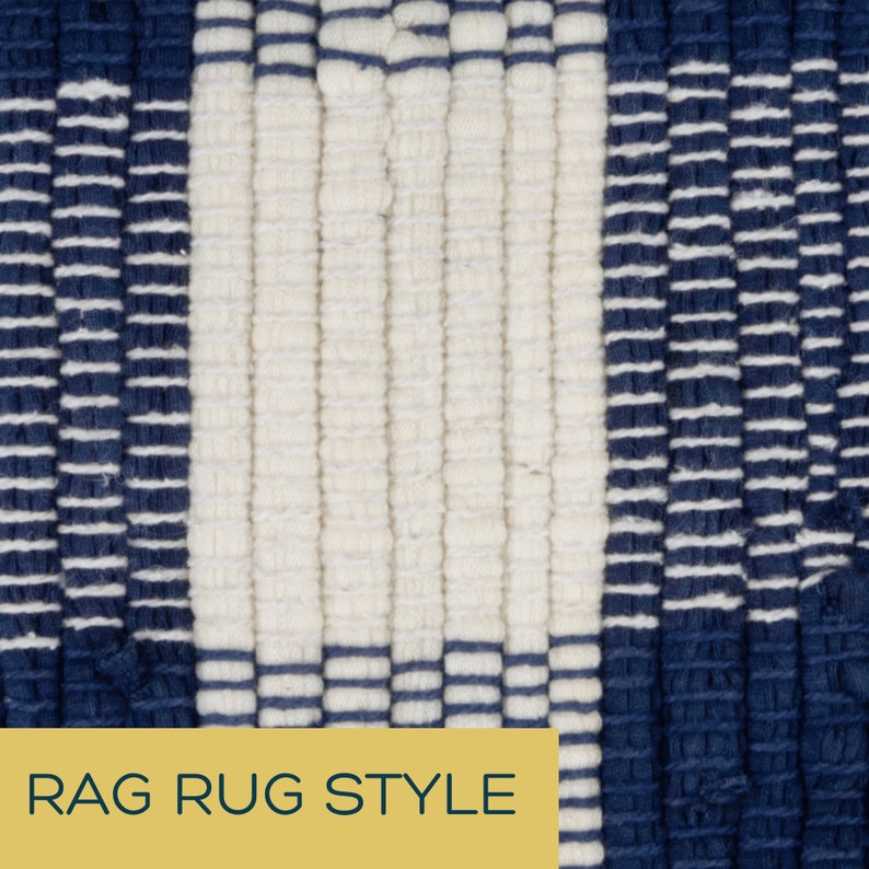 May include: Close-up of a woven rug with a repeating pattern of navy blue and off-white stripes. The rug has a textured surface and the words "RAG RUG STYLE" are printed on a yellow rectangle at the bottom.