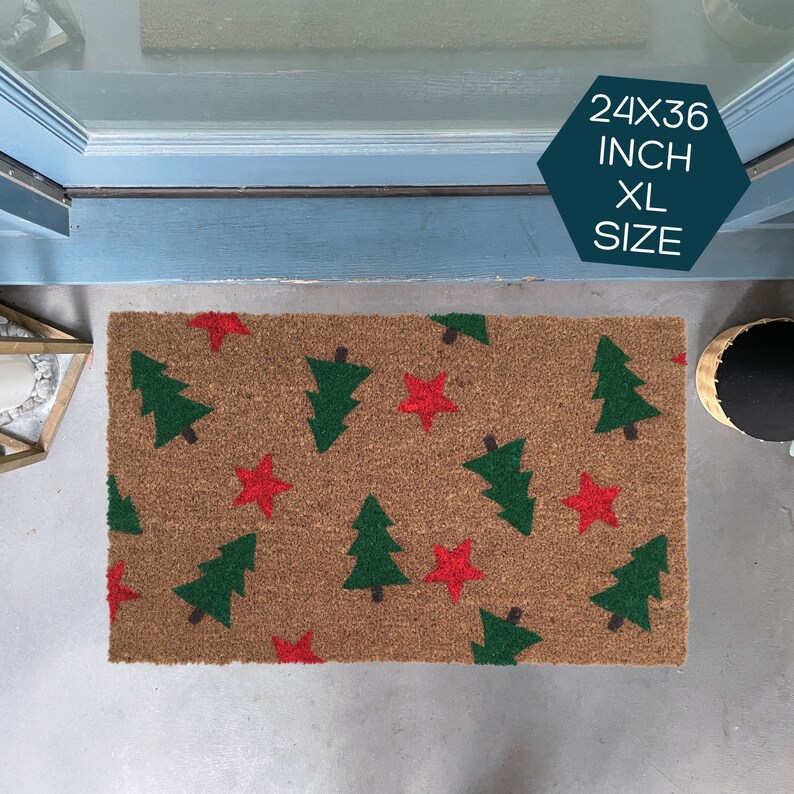 May include: A brown coir doormat with a Christmas tree and star pattern. The mat is 24x36 inches and is labeled "XL Size".