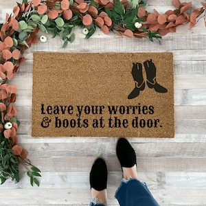 May include: A brown coir doormat with the text "Leave your worries & boots at the door." and a silhouette of two cowboy boots.