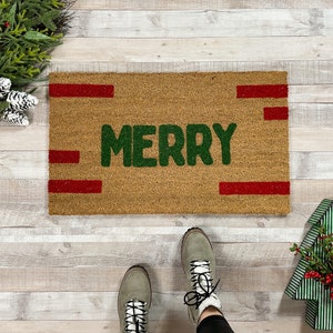 May include: A brown doormat with the word "Merry" in green letters and red stripes across the top and bottom.