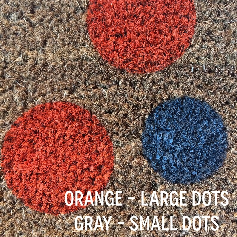 May include: A brown doormat with large orange and blue dots. The text "ORANGE - LARGE DOTS GRAY - SMALL DOTS" is printed on the doormat.