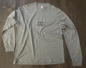 May include: A gray long-sleeve t-shirt with the text "MARTIN & MALCOLM" printed on the front.