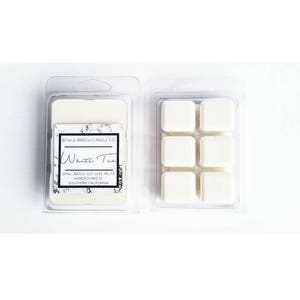 May include: Six white soy wax melts in a clear plastic container with a label that reads "BOW & ARROW CANDLE CO. White Tea SMALL BATCH SOY WAX MELTS HANDPOURED IN SOUTHERN CALIFORNIA"