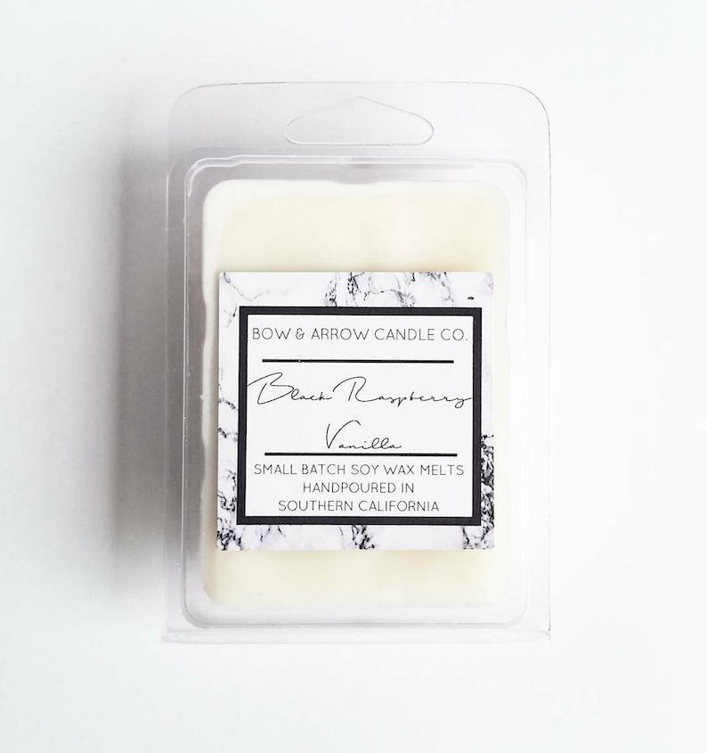 Puede incluir: Un derretimiento de cera de soja blanco en un recipiente de pl&aacute;stico transparente con una etiqueta en blanco y negro que dice "BOW & ARROW CANDLE CO. Black Raspberry Vanilla SMALL BATCH SOY WAX MELTS HANDPOURED IN SOUTHERN CALIFORNIA"