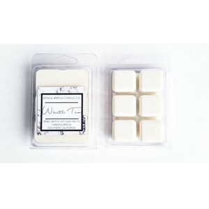 Puede incluir: Seis cubos de cera de soja blanca en un recipiente de pl&aacute;stico transparente. La etiqueta dice "BOW & ARROW CANDLE CO. White Tea SMALL BATCH SOY WAX MELTS HANDPOURED IN SOUTHERN CALIFORNIA."