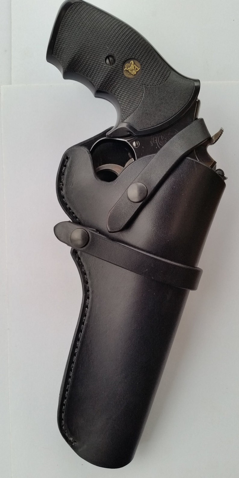 May include: A black leather holster with a snap closure and a belt loop. The holster is designed to hold a revolver.