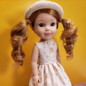 May include: A doll with red hair in pigtails wearing a white crocheted hat, a white dress with a floral pattern, and white shoes.