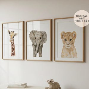 May include: Three framed watercolour prints of a giraffe, elephant, and lion cub. The artwork is displayed on a white wall above a bench. The text "DIGITAL ART PRINT SET" is in a circle in the upper right corner.