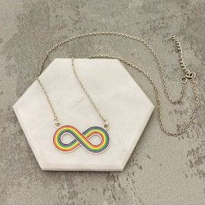 May include: A silver chain necklace with a rainbow infinity symbol pendant.