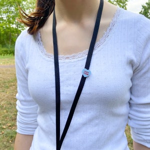 Pronoun pin attached to lanyard shown from another angle demonstrating wearable use