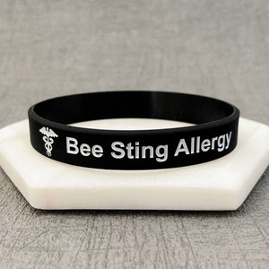 May include: Black silicone bracelet with white text that reads "Bee Sting Allergy" and a medical symbol.
