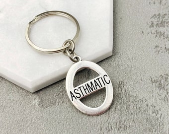 May include: Silver key ring with a round tag that says "ASTHMATIC" in black lettering.